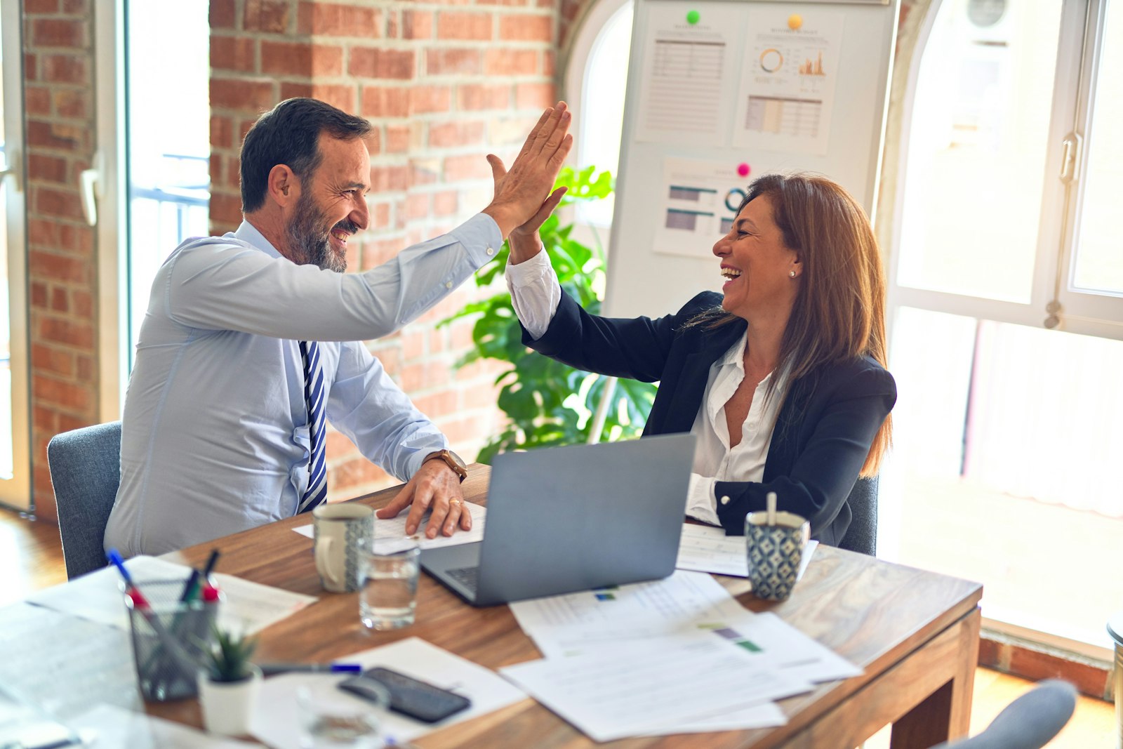 Two colleagues celebrating a closed deal at a desk